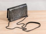 a black purse with a chain on a wooden table