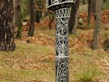 a black and white sign on a pole in the woods