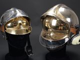 pair of silver and gold helmets on display against a black background