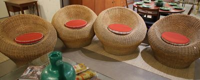 three wicker chairs with red cushions sit in a living room