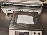 une balance posée par terre, sur laquelle se trouve une feuille de papier
