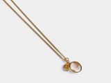 a gold plated necklace with a pink stone pendant on a gold chain