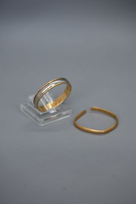 une bague en or et une autre bague en or posées sur une surface blanche
