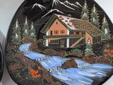 two decorative plates with a painting of a cabin and a stream