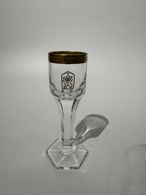 un verre à vin orné d'un bord doré posé sur une table