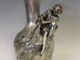 un vase en argent posé sur un socle en bois, sur fond blanc
