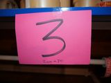 a pink sign with the number 3 on it on a shelf