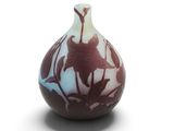 un vase orné d'un motif floral sur une surface blanche