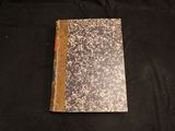 an old book sitting on top of a black cloth covered table