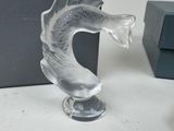 a glass sculpture of a fish on a stand