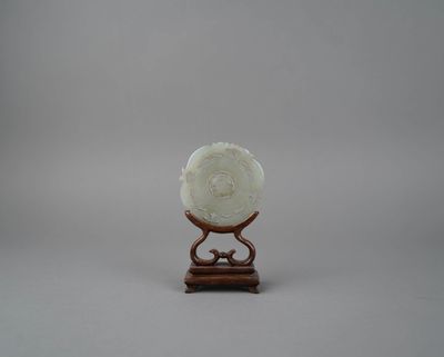 une sculpture en jade blanc représentant une fleur, posée sur un socle en bois