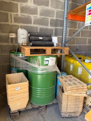 un fût vert posé sur une palette à côté d'une pile de cartons