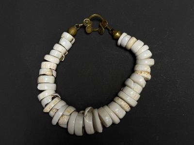 un gros plan d'un bracelet composé de perles blanches sur un fond noir