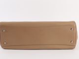 the large tan leather purse is sitting on a white surface