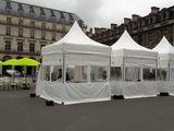 plusieurs tentes blanches avec des parasols jaunes devant une rangée de bâtiments