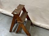 a small wooden step stool next to a white wall