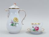 a white and gold coffee pot with a cup and saucer