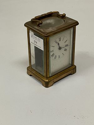a small brass clock with roman numerals on the face