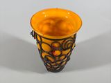 orange and black glass vase with a decorative design on the rim