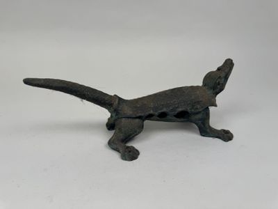 une vieille figurine en bronze représentant un chat, posée sur une surface blanche