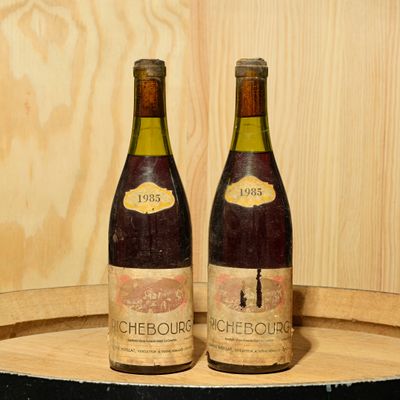 two bottles of wine sitting on top of a barrel