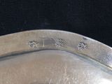 a close up of a silver plate with a black background