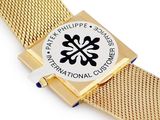 yellow metal mesh strap with a white and black logo on it