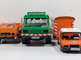 three toy trucks sitting next to each other on a white surface