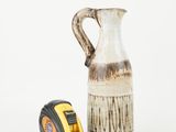 a picture of a measuring tape next to a ceramic jug