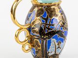 a blue vase with a gold handle on a white background