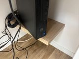 a computer on a wooden shelf with a power cord