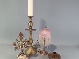 une bougie, un bougeoir, une lampe et d'autres objets posés sur une table