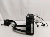 a black camera sitting on top of a white table next to a charger