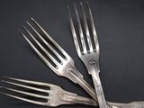 four forks are arranged on top of each other on a black surface