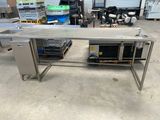 table de travail en acier inoxydable dans un entrepôt, avec un homme à l'arrière-plan
