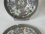 two plates with designs on them sitting on a white surface