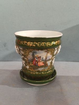 a green and white vase with a painting on it