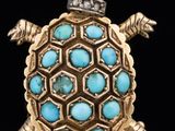 a close up of a turtle broochle with a purple stone in its shell