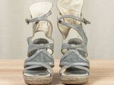 pair of women ' s sandals on a wooden table with a curtain in the background