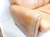 a brown leather couch sitting next to a chair in a room