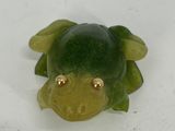 a green frog that is laying down on a white surface