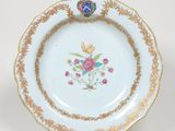 une assiette blanche bordée d'or et décorée de fleurs