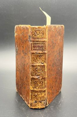 an old book sitting on a table with a green leaf sticking out of it