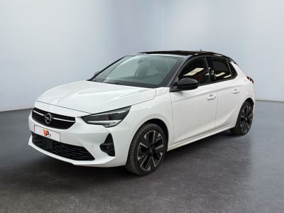 Une voiture blanche est garée dans une pièce au sol noir.
