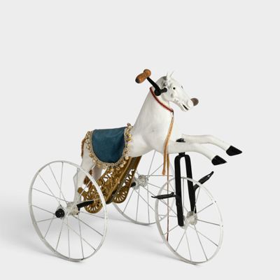 a toy horse riding a bicycle on a white surface