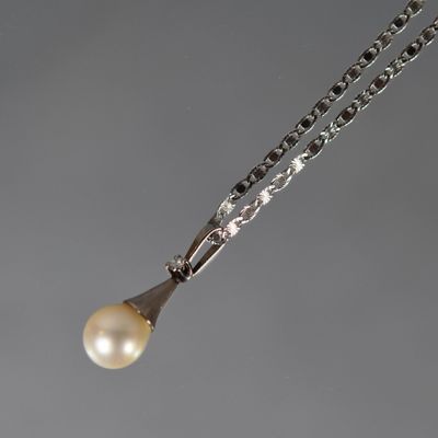 une photo d'un collier composé d'une perle blanche et d'un pendentif en argent, monté sur une chaîne en argent