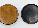 an old black and brown tin with a newspaper on top of it