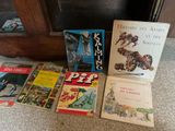several children ' s books are lined up on the floor in front of a fireplace