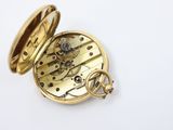 an antique pocket watch on a white surface with a white background