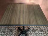 a wooden table with a metal base on a tiled floor